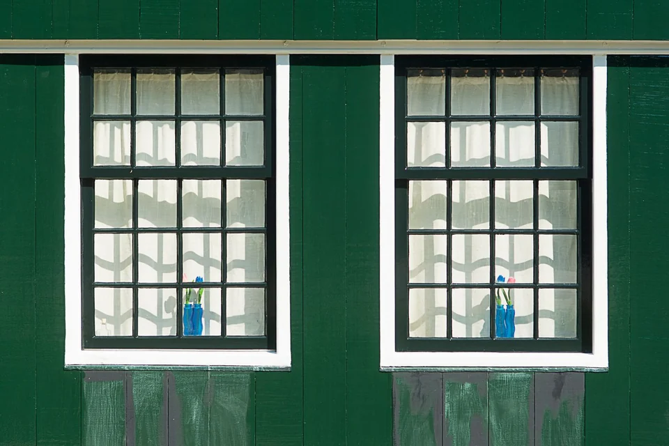 Groen geschilderde houten gevel met witte kozijnen