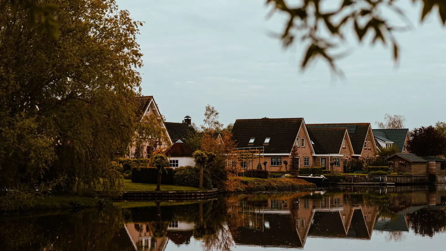 Woonhuizen aan een waterpartij in een Nederlandse woonwijk, weerspiegeld in het water